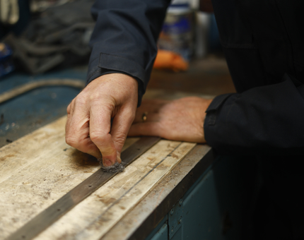 A close up of a hand cleaning a window surround from the Royal Barge. 