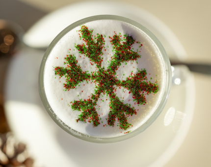 A view of a peppermint hot chocolate from above. It has a glittery green and red snowflake on it. 