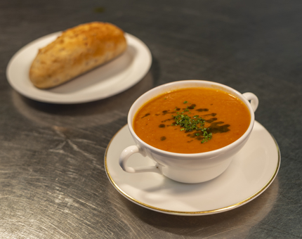 A bowl of roasted red pepper soup and a bread roll in Britannia's galley. 