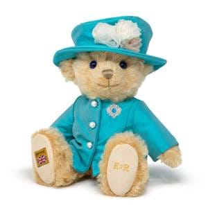 Merrythought HM The Queen Elizabeth II bear sits down wearing a blue jacket and hat.