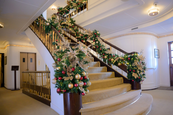 A grand staircase with Christmas decoration on the railings