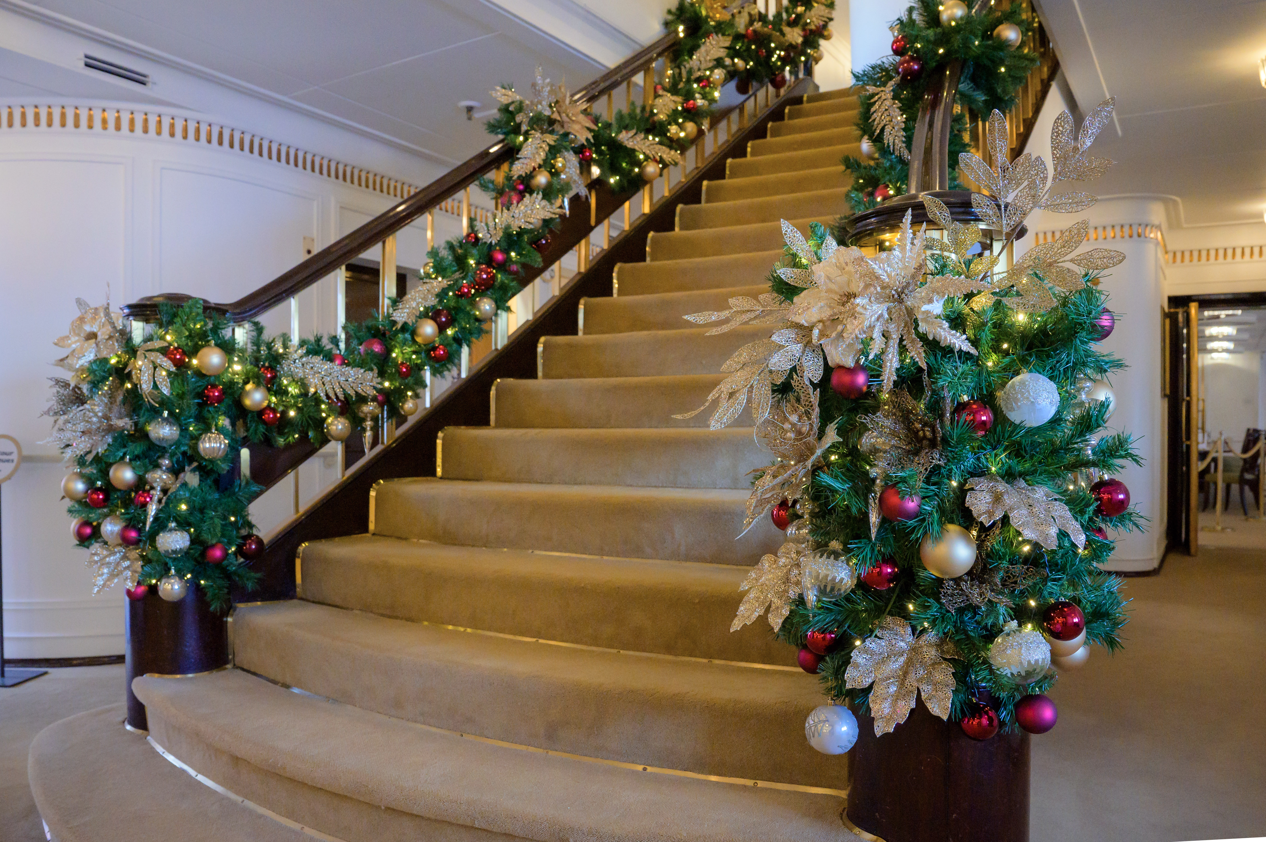 A grand staircase with Christmas decoration on the railings