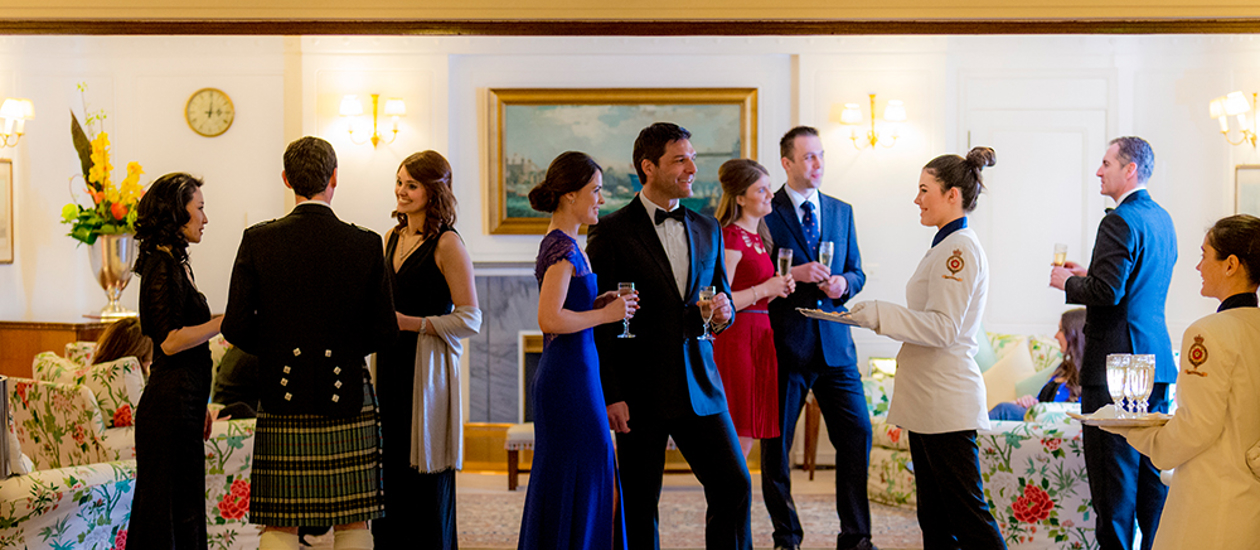 Guests mingle in the State Drawing Room being served drinks. 