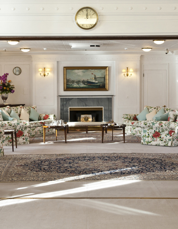 Inside Britannia's State Drawing Room. Armchairs around a fireplace.
