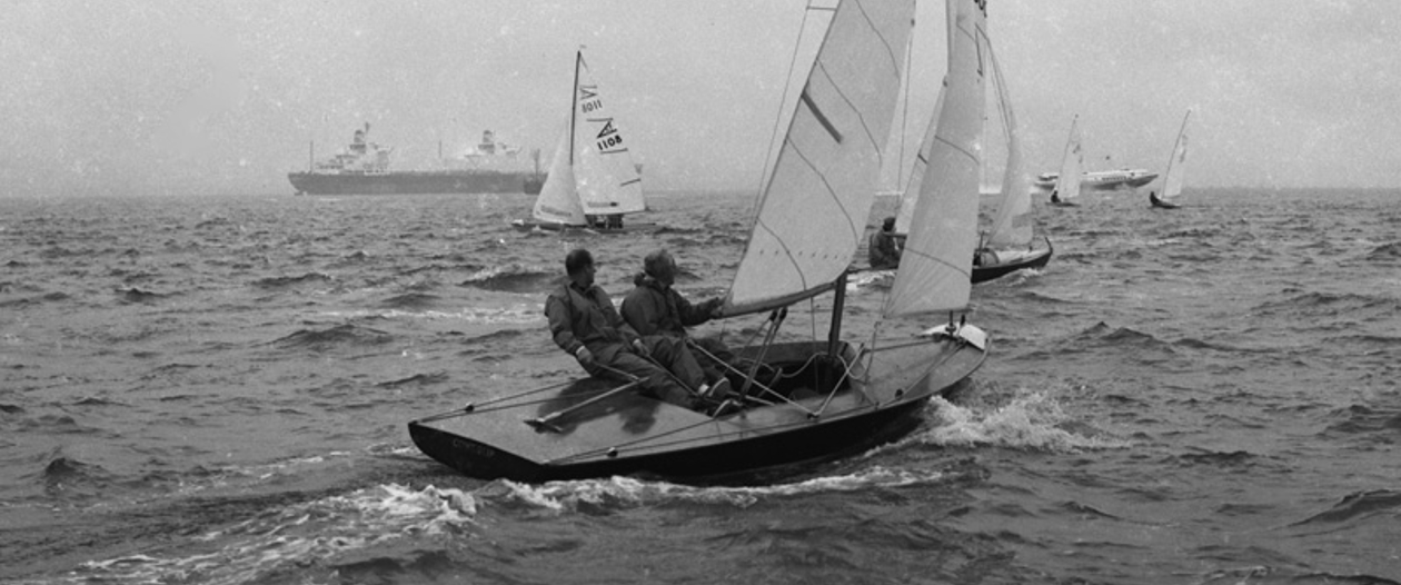 A black and white image of a small sailing yacht in Cowes. 
