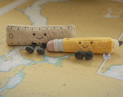 Two Jellycat Amuseable plush toys, one is a ruler and one is a pencil. 