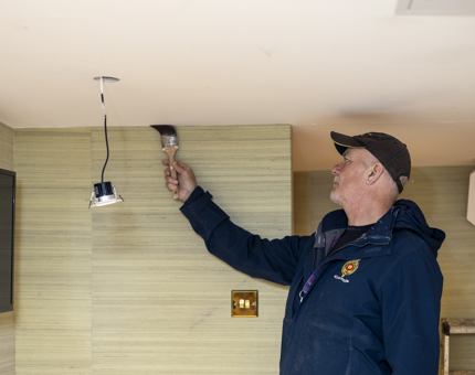 A man from the Maintenance team is painting the ceiling in a cabin at Fingal. 