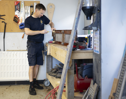 A Maintenance man is sanding a scupper board. 