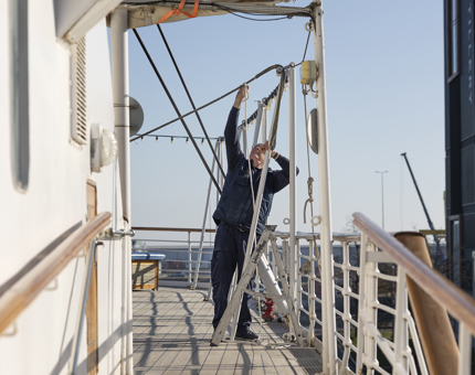 A Maintenance man preparing ropes to lift the awning on the Verandah Deck. 