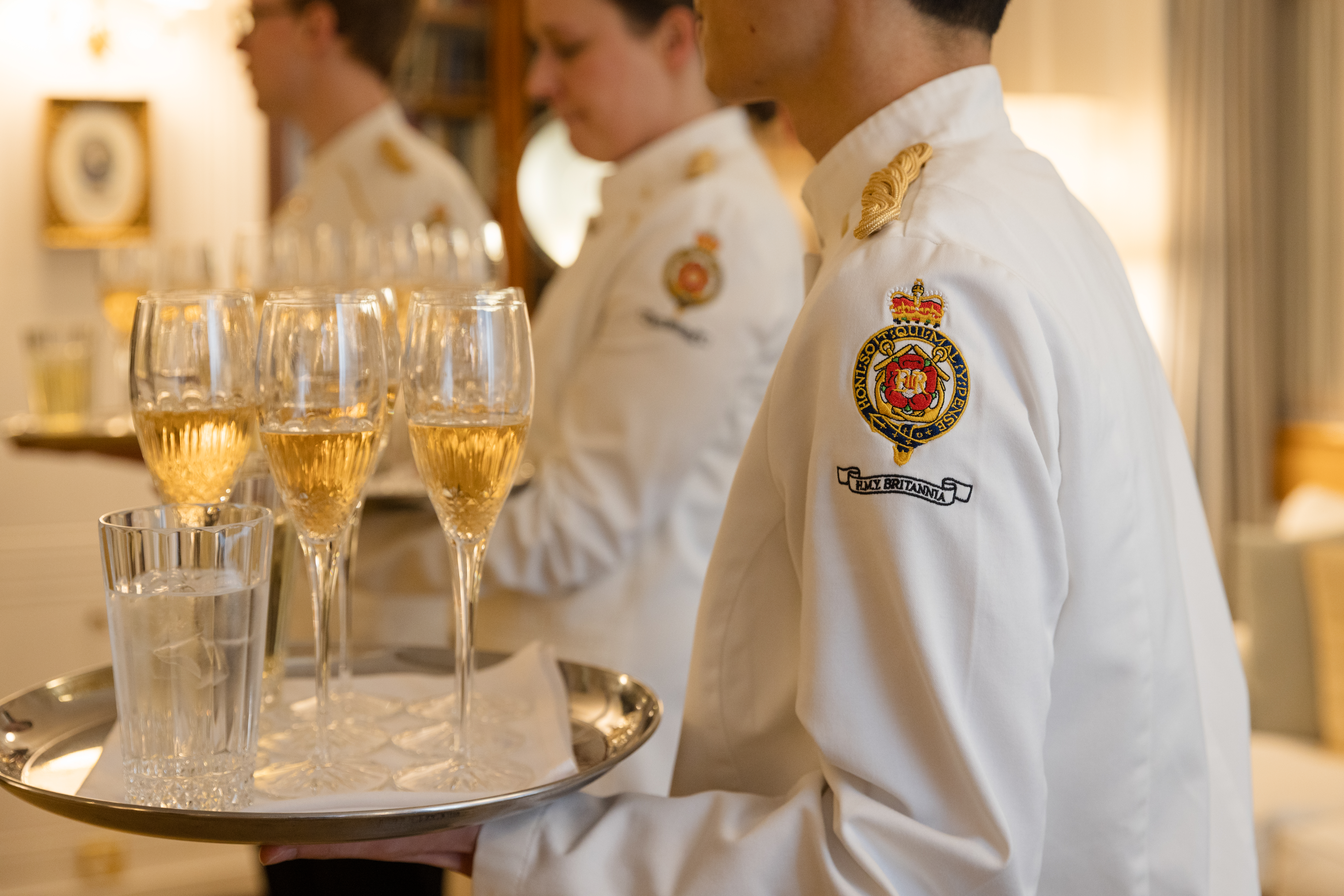 Men and women carrying trays of glasses