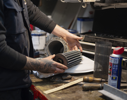 A close up of hands reassembling an oil filter from the Royal Barge.