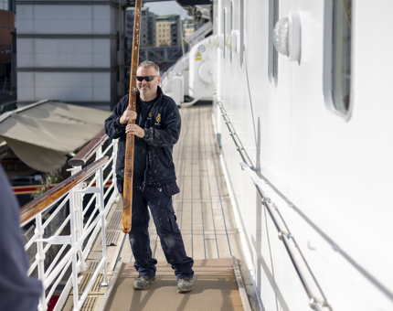 A Maintenance team member is carrying a wooden handrail to be installed on Britannia in Leith. 