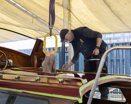 A maintenance man is painting the roof of the Royal Barge next to Britannia. 