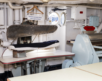 In Britannia's onboard Laundry, there is a trouser press with a pair of trousers in it. 