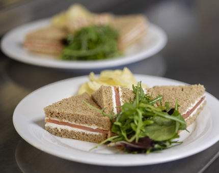 Two salmon sandwiches are on white plates, ready to be served from the Galley. 