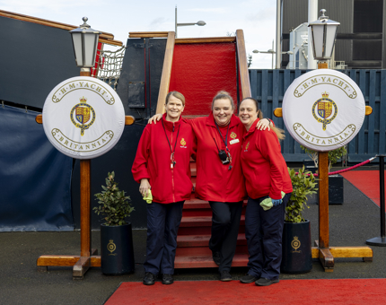 Three Housekeepers pose for a photo at the bottom of the Royal Brow in Leith. There are two Lamp posts with perry bouys with the Britannia crests. 