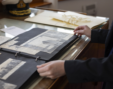 A close up of hands on the pages of a scrapbook from Britannia's archives. 