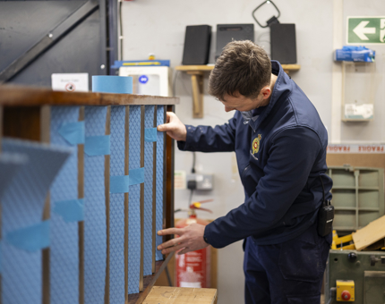 A maintenance team member is adding non-slip tread to a set of steps