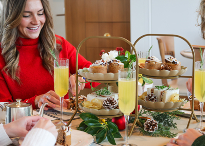 Woman smiling enjoying festive cream tea. 