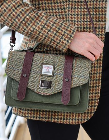 A woman is wearing an Islander tweed satchel bag.