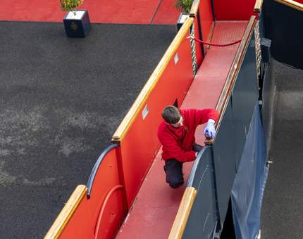 A Housekeeper is crouching down on the Royal Brow to clean the side of it. 
