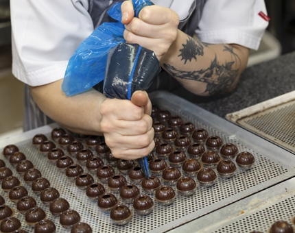 A Close Up Look Of Caramel Being Piped Into Chocolate Petit Fours