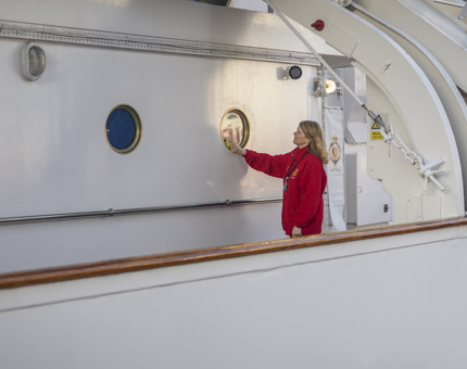 A Housekeeper is polishing a porthole aboard The Royal Yacht Britannia. 