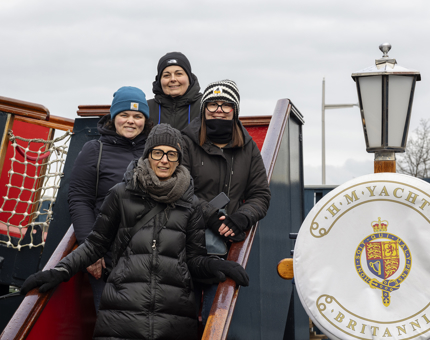 A group of four people standing on the stairs to the Royal Brow at The Royal Yacht Britannia in Leith. 