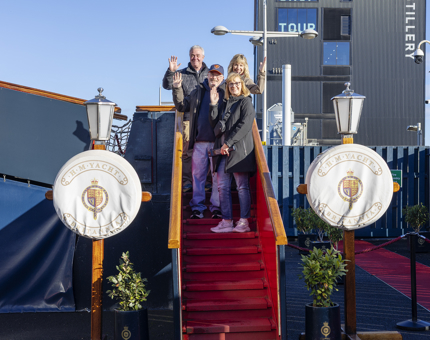 Four visitors posing for a photo on the stairs of the Royal Brow at The Royal Yacht Britannia. 