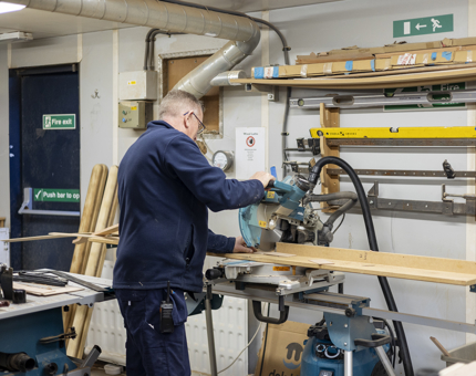 A maintenance man is cutting wood to make a frame for the Royal Barge. 