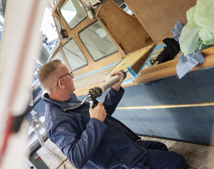 A closer look a maintenance man caulking the Royal Barge. 