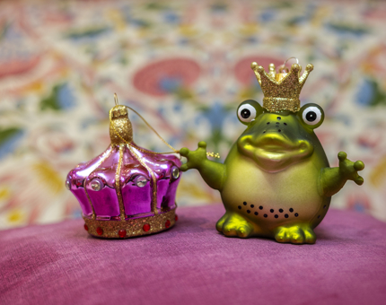 two hanging decorations, one is a frog with a crown, the other is a purple and gold crown. 