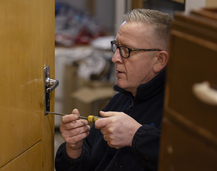 Mark repairing a lock on the Shop stock room