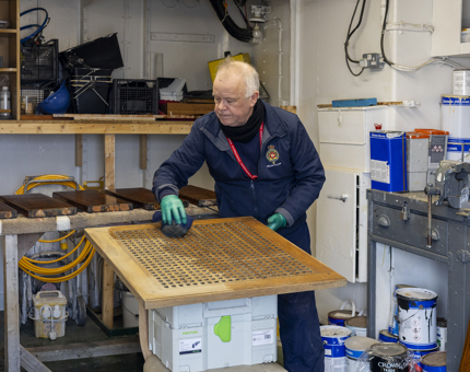 A Maintenance man is oiling a scupper board from the Funnel Deck aboard Britannia. 