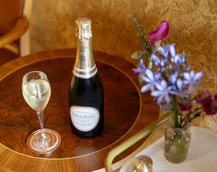 A bottle and a glass of Champagne are sitting on a brown round table aboard Fingal. 