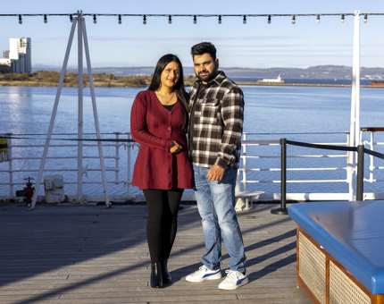 A man and woman stand on the Verandah Deck of The Royal Yacht Britannia Edinburgh. 
