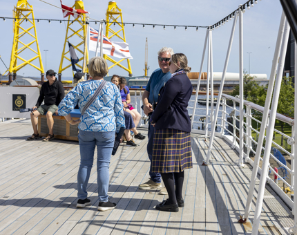 A Visitor Assistant chats to visitors on the Verandah Deck in Leith.