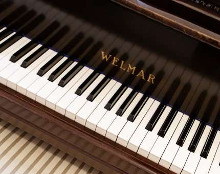 A close up of a Welmar grand piano. 
