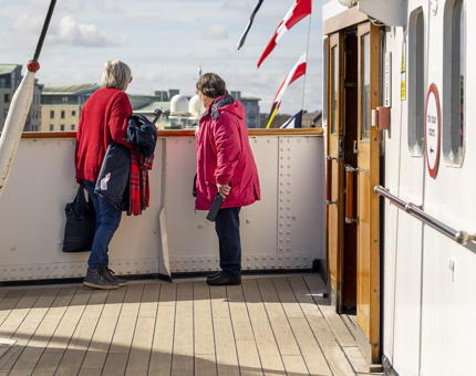 Two ladies wearing red jackets, looking at the view from the Bridge. 