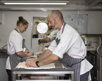 Three chefs in the Galley making bread rolls.