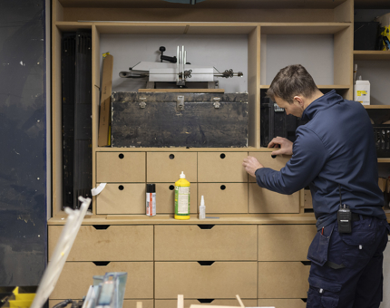 A maintenance team member building a storage unit in the workshop. 