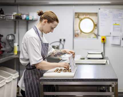 A Chef is in the Royal Galley taking whisky and orange bon bons out of a mould. 