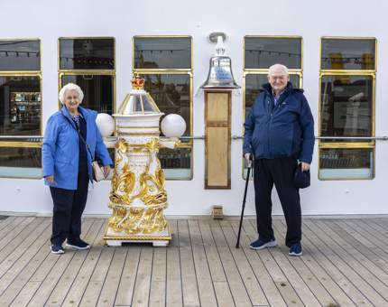 A man and woman pose for a photo by The Royal Yacht Britannia's Bell and binnacle in Edinburgh. 