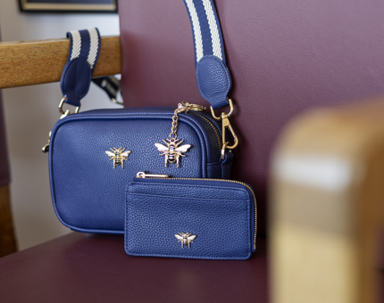 A blue Araminta Campbell cross body bag, key ring and purse with gold bee detail. 