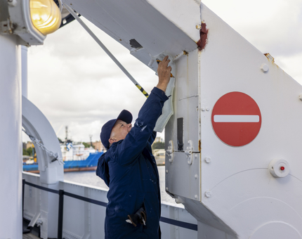 A maintenance man is measuring up fiber glass to repair hole in metal work. 