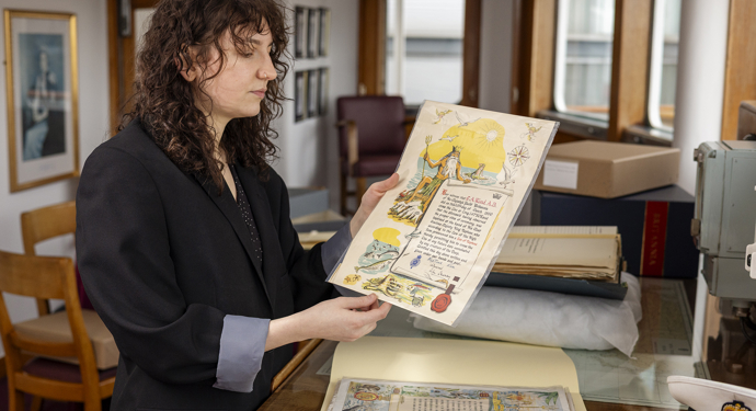 The archivist is holding up an illustrated document from Britannia. 