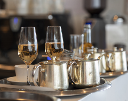 Trays of drinks, including glasses of pink fizz and tea pots, are sitting on the bar, waiting to be served. 
