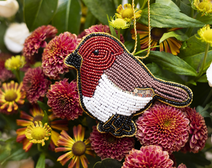 Beaded robin hanging decoration sitting against flowers. 