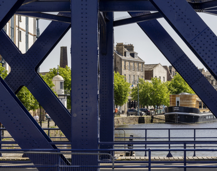 A view through the Victoria Swing Bridge of the boats and buildings at the Shore in Leith. 