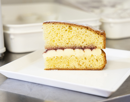 A slice of Victoria Sponge Cake on a white place. 